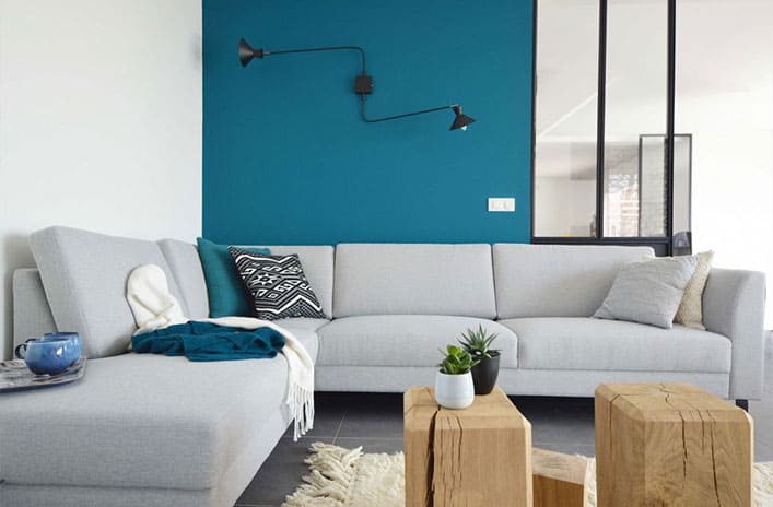 Salon chic avec mur bleu canard et canapé gris clair