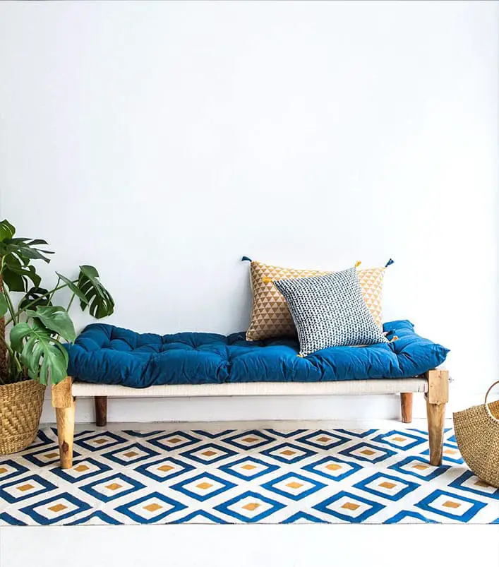 Banquette bleu roi avec tapis géométrique et coussins de couleurs
